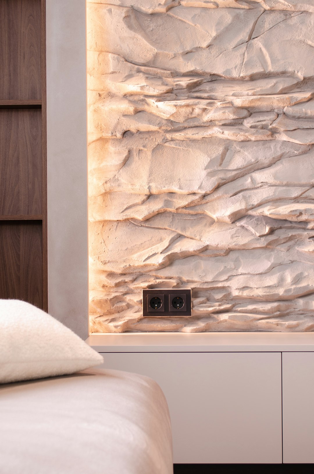 a-bedroom-with-a-white-bed-and-a-stone-wall-upq3qggmngi